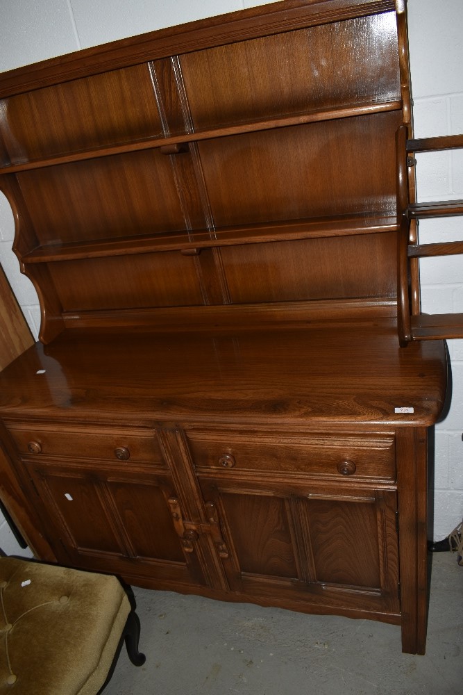 An Ercol mid elm dresser having shaped Delft rack over drwers and cupboards, w123cm