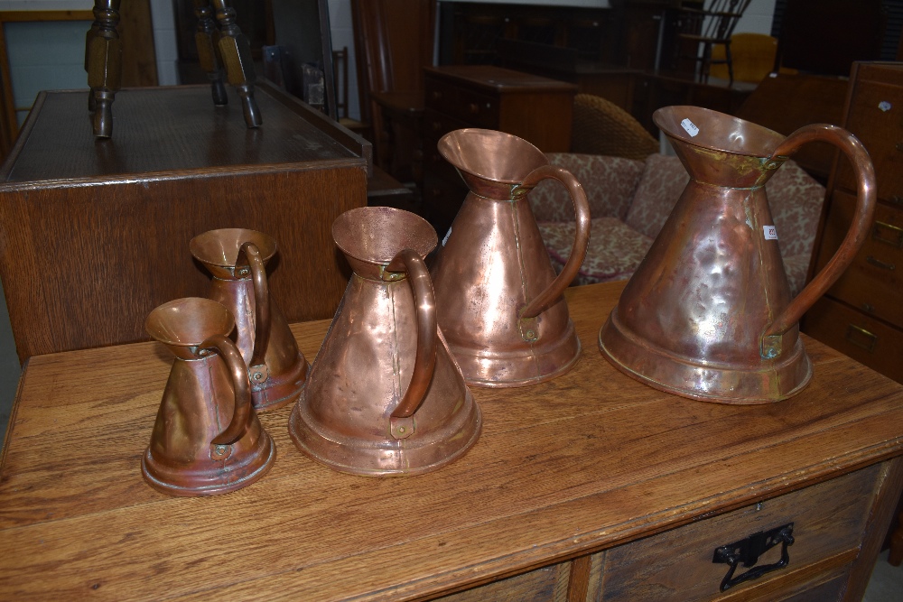 A set of five graduated copper jugs