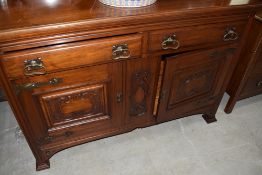 A late Victorian Art Nouveau reduced back sideboard having drawers and carved cupboards