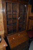 A 1920's oak bureau bookcase having panel glass over fall front and drawers, w 74cm