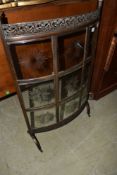 An Edwardian burnished metal bow front fire screen having cut glass panels