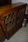 A late C20th oak Jacobean style bookcase having leaded glass top over linen fold cupboard base, w