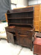 An early 20th Century dark oak dresser having Gothic style decoration to doors and shelf back