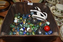 A wooden box containing a large amount of vintage marbles.