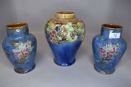 Three early 20th century Royal Doulton vases having blue ground with flora, butterflies and fruits.