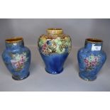 Three early 20th century Royal Doulton vases having blue ground with flora, butterflies and fruits.