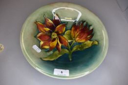 A Moorcroft dish having green ground with Sunflower or similar to centre.