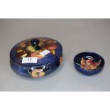 Two pieces of vintage Moorcroft, a lidded pot having blue ground with orchid design(AF) and a