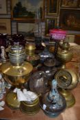 A selection of antique oil lamps and useful parts, one having cranberry glass reservoir and