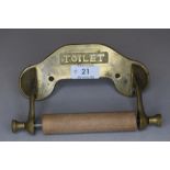 A Vintage brass and wood toilet roll holder.