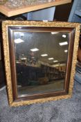 A vintage wooden framed mirror having gilded floral decoration.