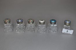 Six vintage cut glass bottles or jars having guilloche lids with floral details.