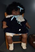 A doll and a small wicker chair.