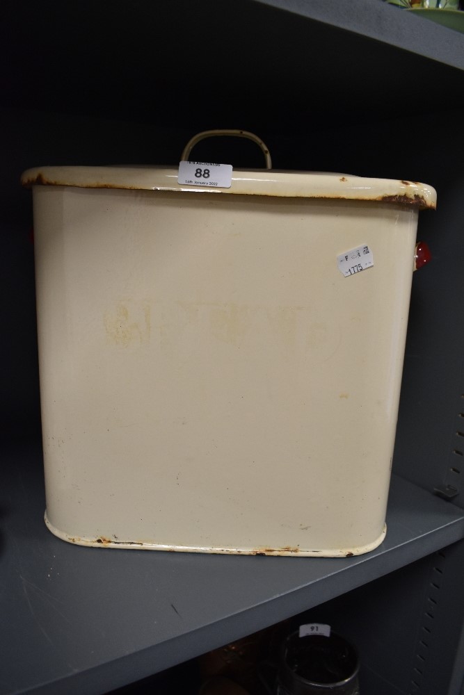 A 1940s cream enamel bread bin having red handles.