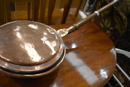 A copper and turned handle bed warming pan