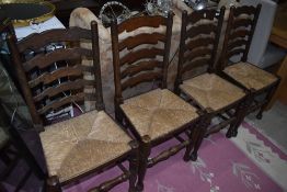 A set of four traditional oak ladder back chairs having rush seats