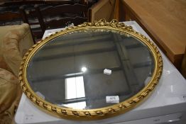 A gilt frame circular wall mirror having foliate bow decoration