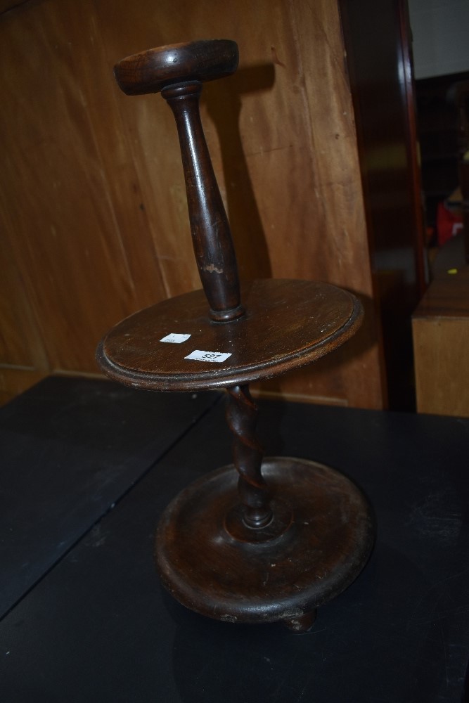 An early 20th Century oak candle of similar stand having lower twist column