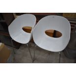 A pair of modernist designer style chairs having chrome legs and white perspex seats