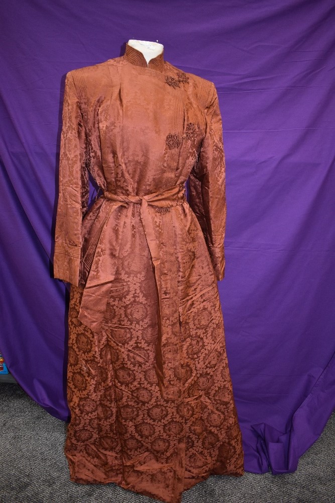 A full length Chinese dressing gown or house coat in terracotta silk or silk blend fabric, frog