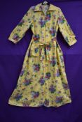 A full length late 1940s/early 50s yellow house coat with vibrant floral pattern, belted waist,3/4
