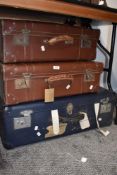 Three vintage suitcases, two brown and one larger blue one.