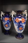 A pair of late 19th early 20th century vases, both tall and having handles, with floral pattern to