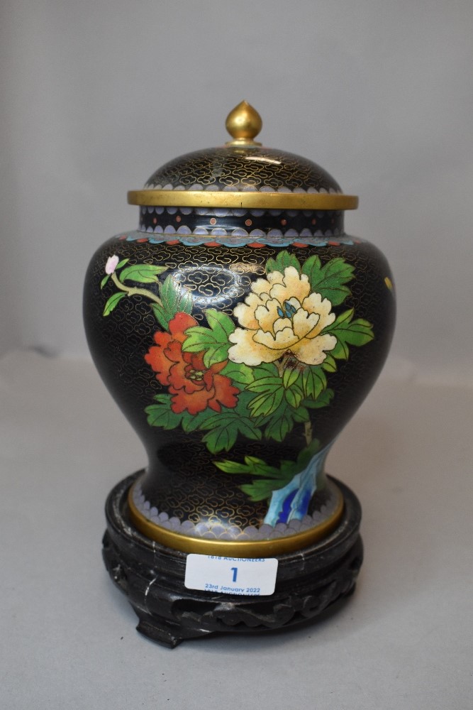 A cloisonne lidded ginger jar decorated with floral scenes on wooden stand