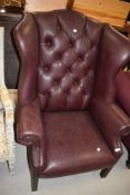 A modern Georgian style wing back armchair, having burgundy leather uphostery