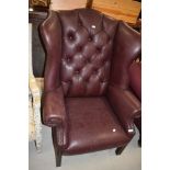 A modern Georgian style wing back armchair, having burgundy leather uphostery