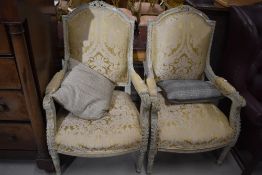 A pair of Louis XV inspired armchairs having brocade upholstery and ornate highlighted carved