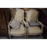 A pair of Louis XV inspired armchairs having brocade upholstery and ornate highlighted carved