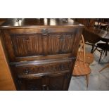 A mid to late 20th Century oak drinks cabinet having linen fold door