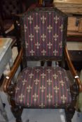 An early/mid 20th century oak armchair having foliate chamfered back with re-upholstered panels