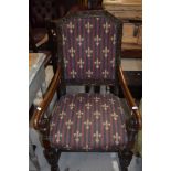 An early/mid 20th century oak armchair having foliate chamfered back with re-upholstered panels