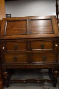 An early/mid 20th century oak bureau having 2 drawers, and cup and cover supports, w 75cm