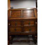 An early/mid 20th century oak bureau having 2 drawers, and cup and cover supports, w 75cm