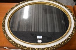 A vintage oval wall mirror, gilt plaster with white trim, width approx 56cm max.