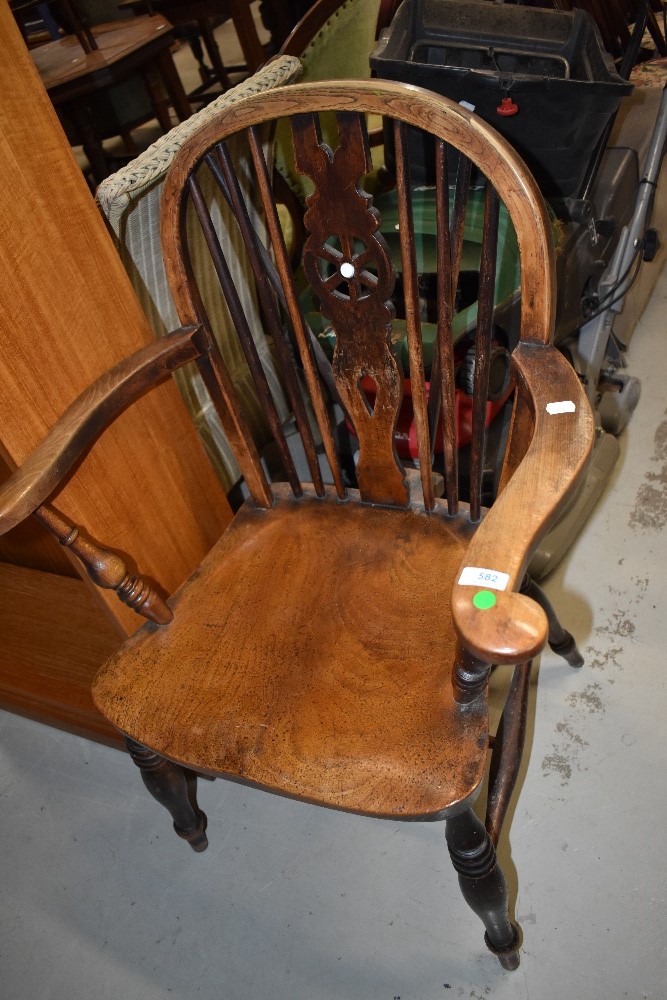 A vintage beech and elm Windsor armchair, having wheel back, solid seat and H stretcher