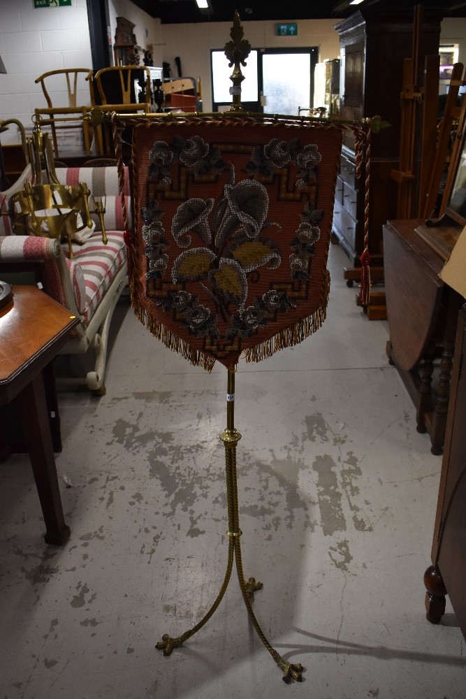 A Victorian brass pole screen having triple twist legs culminating in claw feet, with beadwork