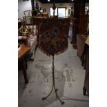 A Victorian brass pole screen having triple twist legs culminating in claw feet, with beadwork