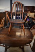 A dark stained Ercol drop leaf table and three (two plus one) dining chairs