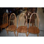 A set of four beech hoop and stick back kitchen chairs, labelled Ercol, mid to light colour