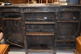 A late Victorian dark oak breakfront bookcase having carved decoration, w 184cm