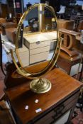 A modern brass oval dressing table mirror