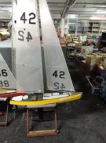 A radio controlled model sail boat GBR2242 with sail and spare sail, on wooden stand, height