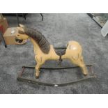 A reproduction wooden Rocking Horse having carved mane, leather saddle with one stirup, missing tail