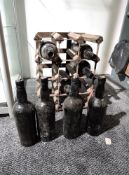 A wooden Wine Rack containing 4 old empty Port bottles and 4 old bottles with varying levels said to