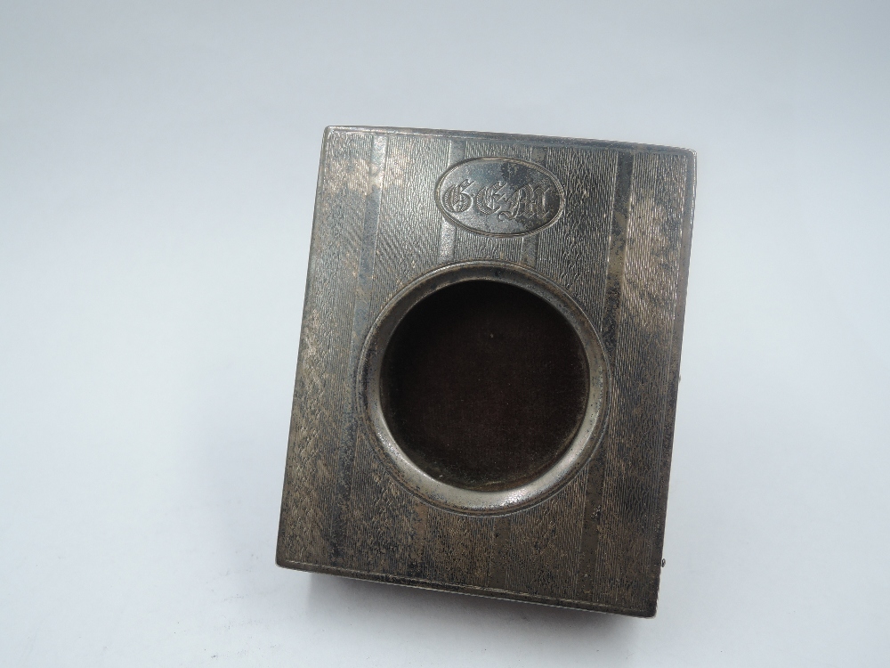 A small silver watch stand having engine turned decoration and monogrammed cartouche to silver