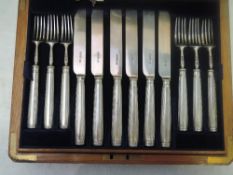 An oak canteen of a 12 person setting of Edwardian silver dessert knives and forks, Sheffield